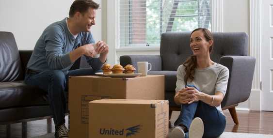 A couple sitting on the floor around a moving box